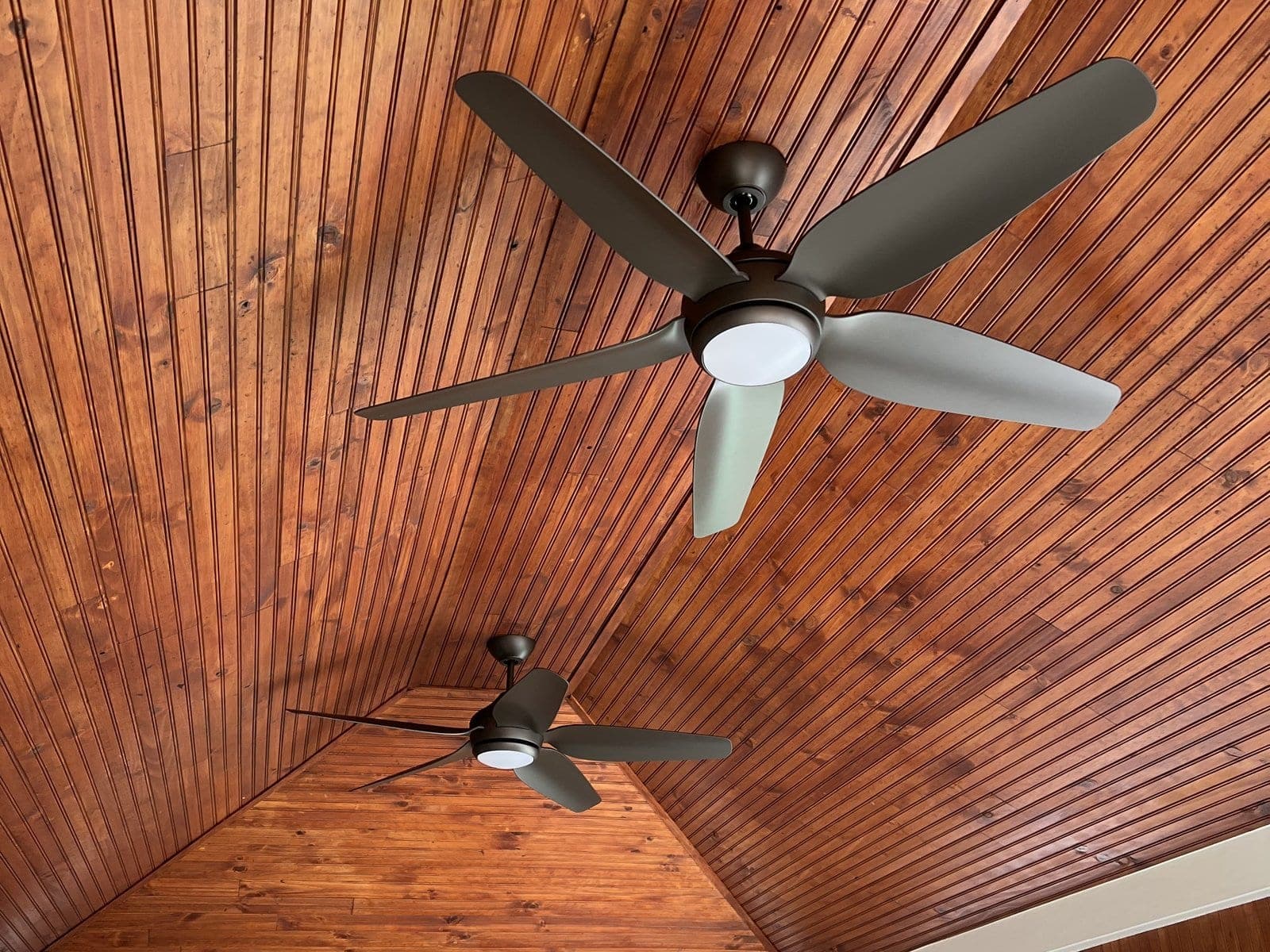 Dual ceiling fans on vaulted wood porch ceiling
