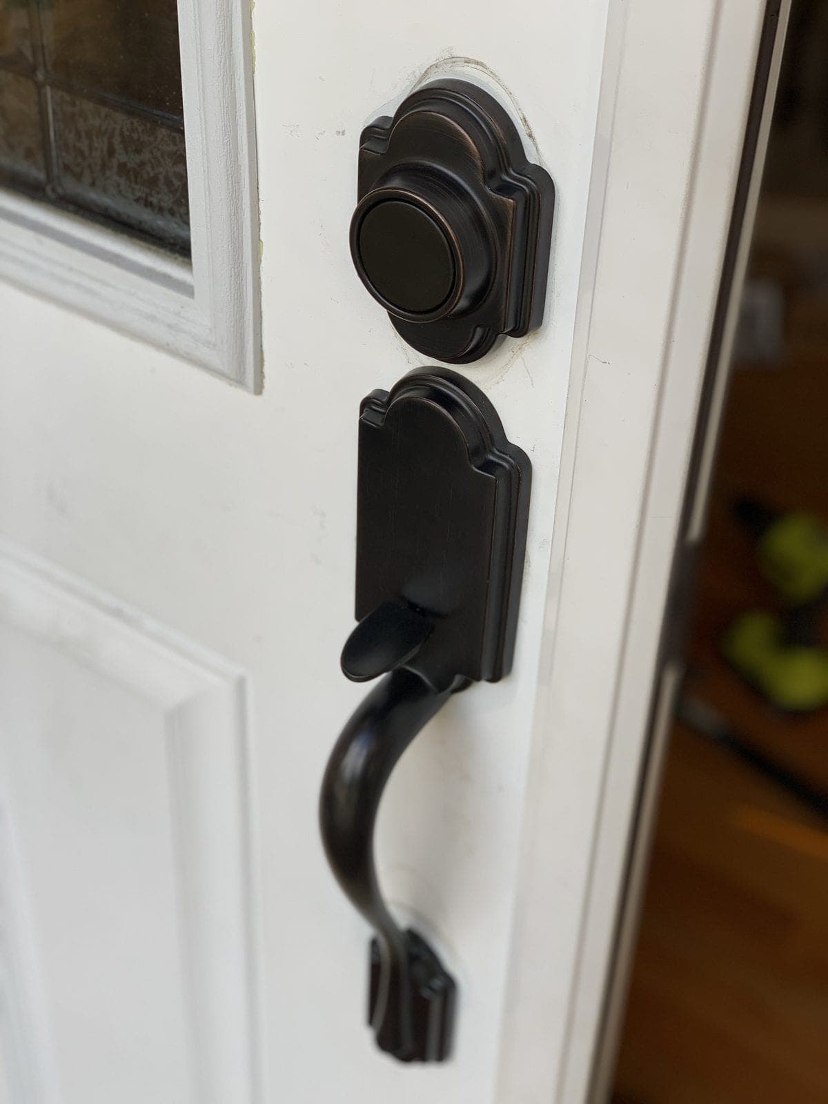 Oil-rubbed bronze smart deadbolt and matching handle set on a white exterior door